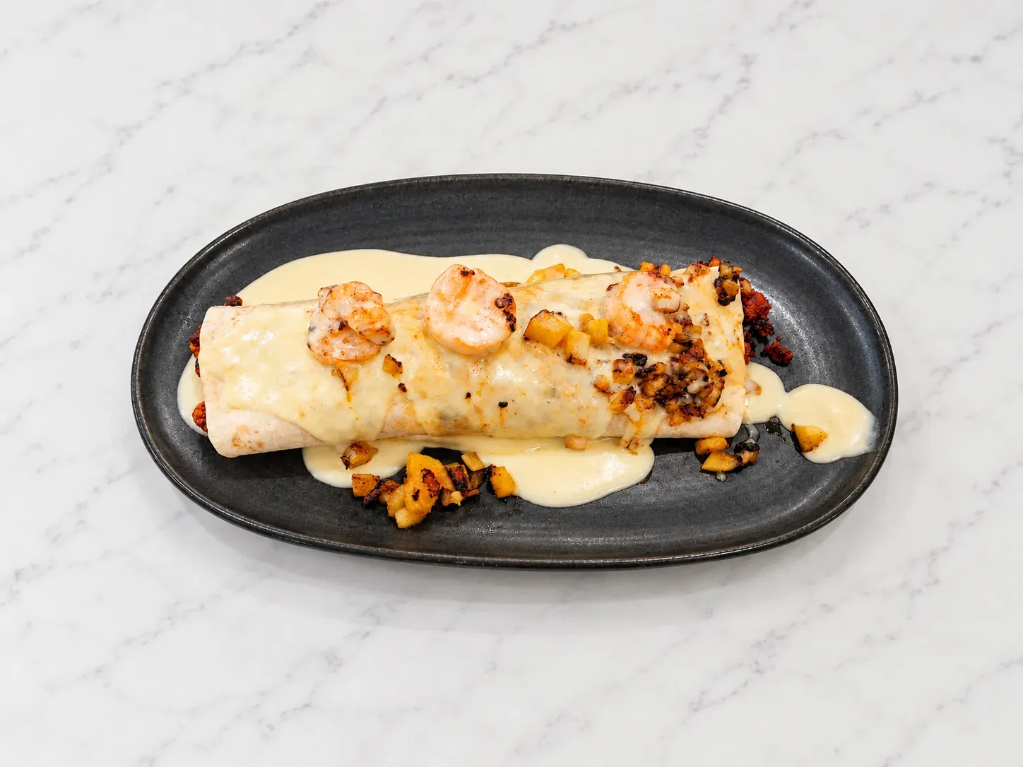 Burrito Aruma with grilled chicken, steak, chorizo, shrimp, pineapple, and cheese sauce