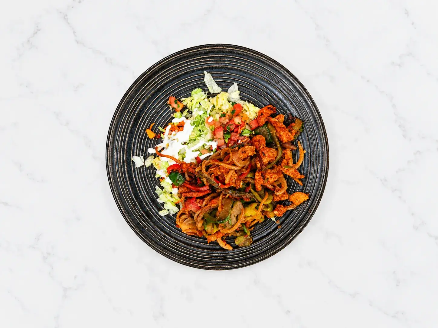A chicken fajita bowl with rice, beans, and peppers