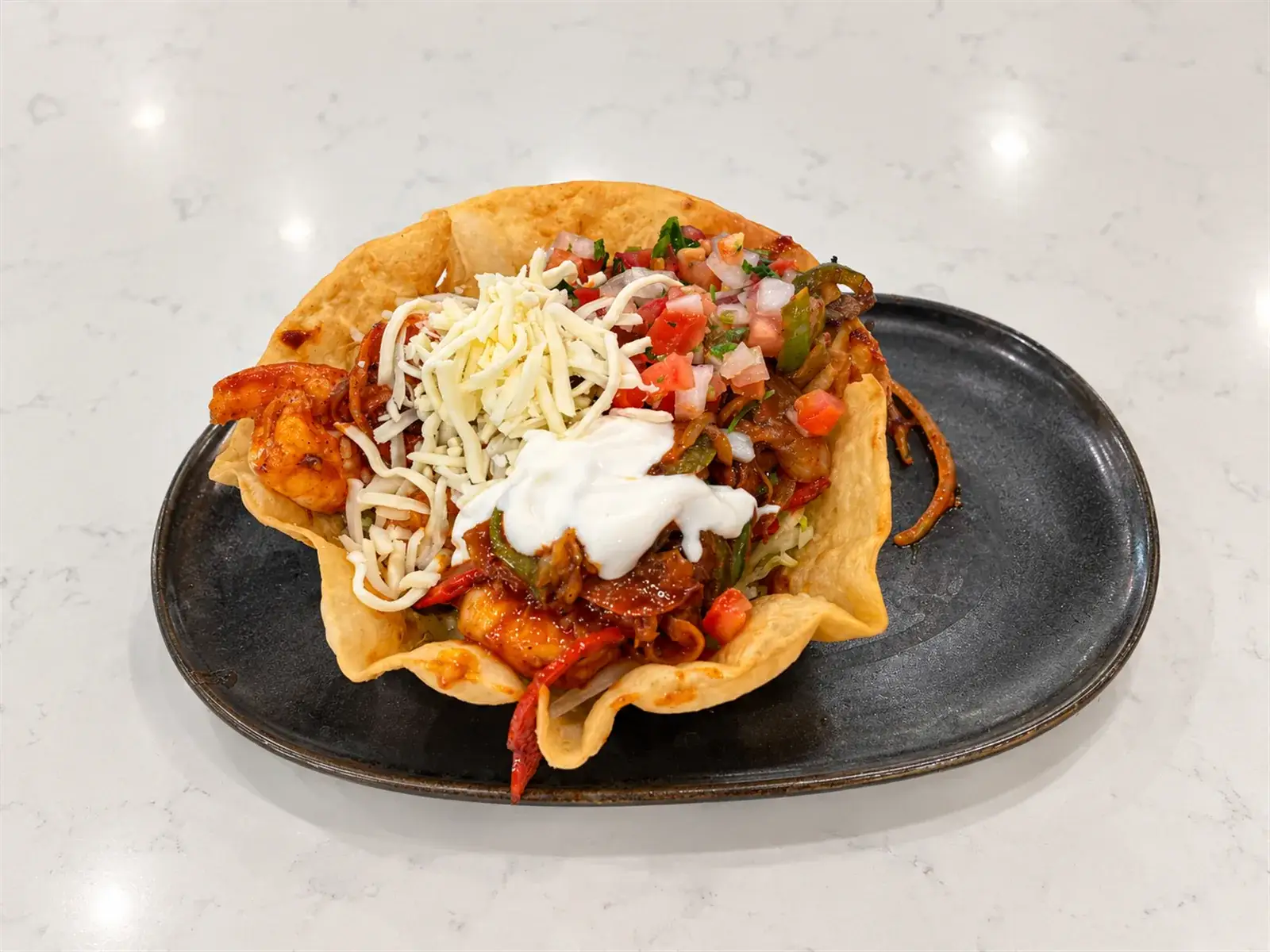 A fajita taco salad with grilled meat, lettuce, and pico de gallo