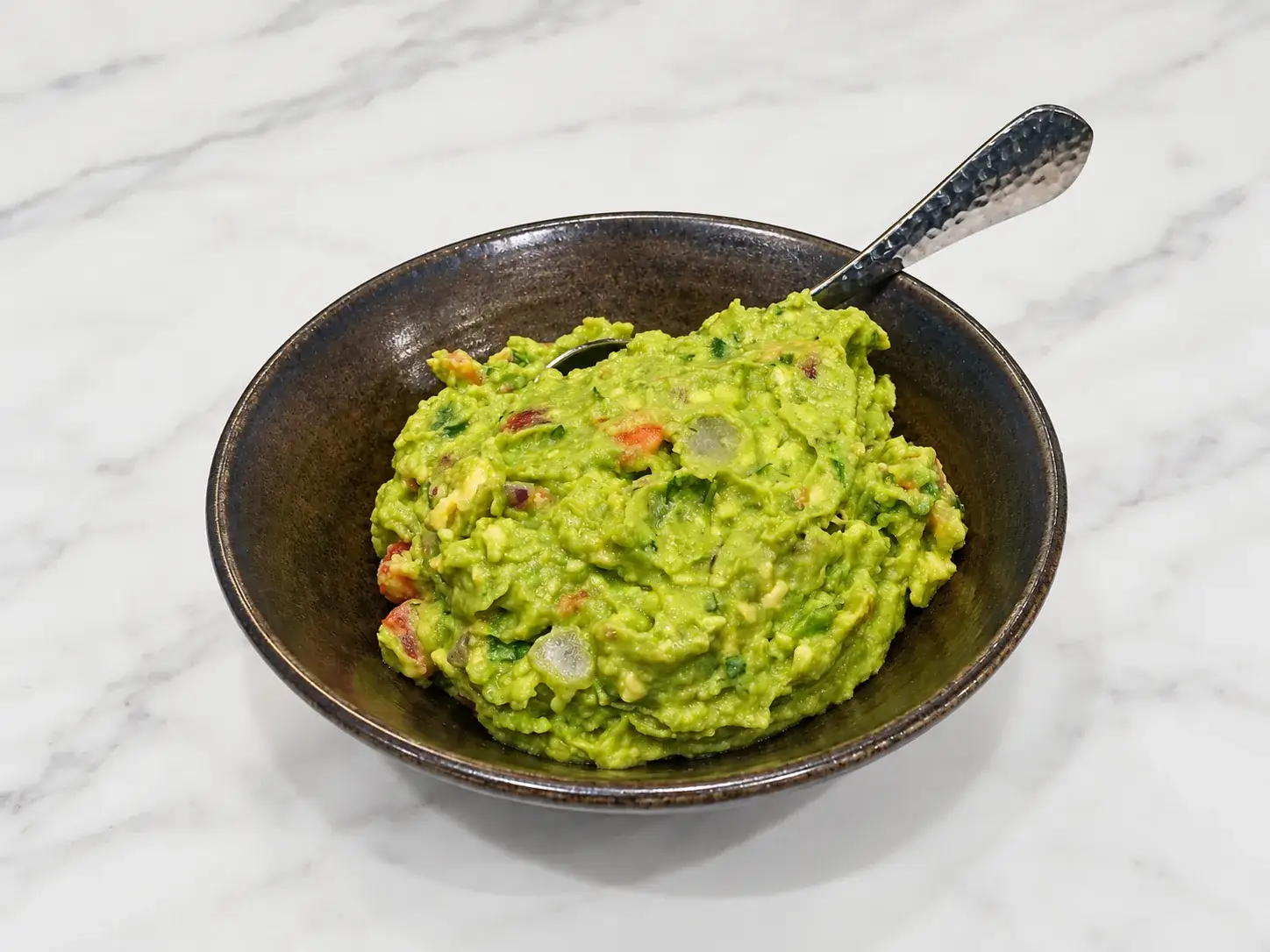 Fresh guacamole in a dark bowl