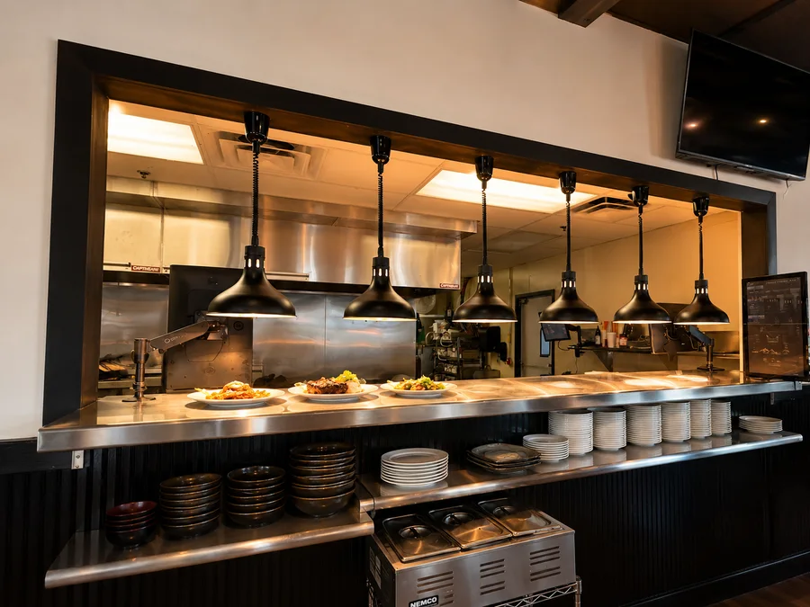 Plates waiting beneath the kitchen pass lights