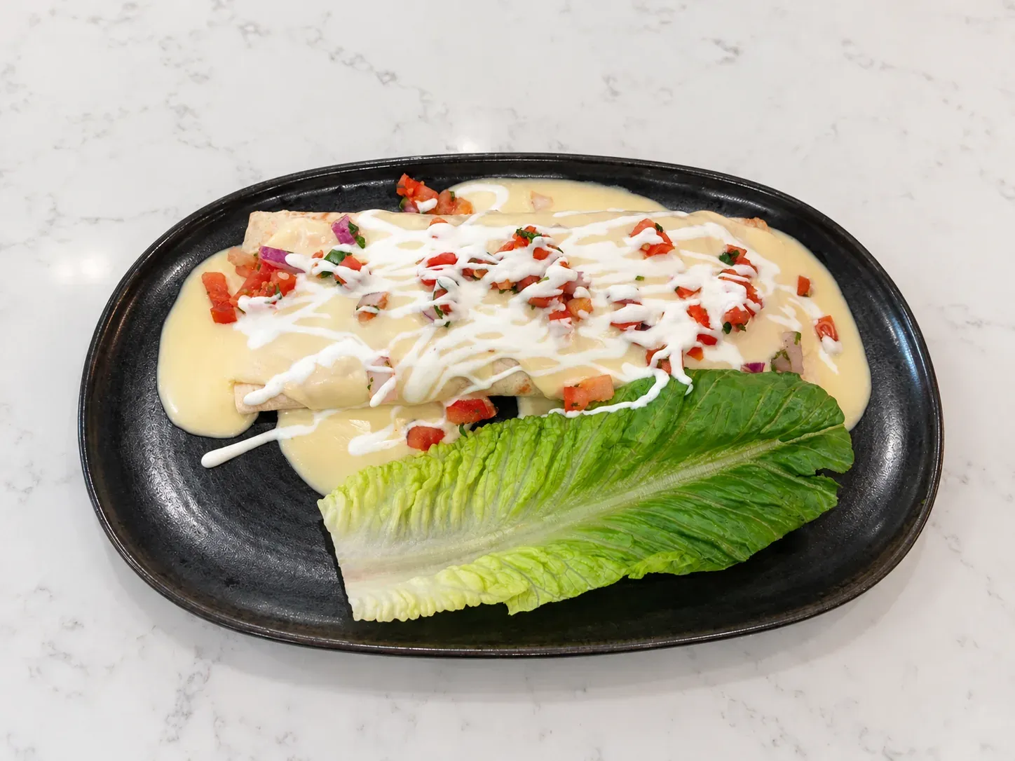 Supreme burrito with ground beef, queso, lettuce, pico de gallo, and crema